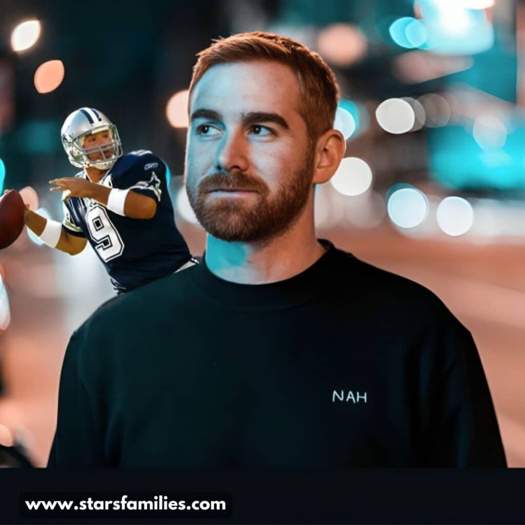 In a nighttime street scene, Andrew Santino is dressed in a black shirt that says "NAH." A miniature American football player, wearing a blue and white uniform with the number 9, is perched on his shoulder.