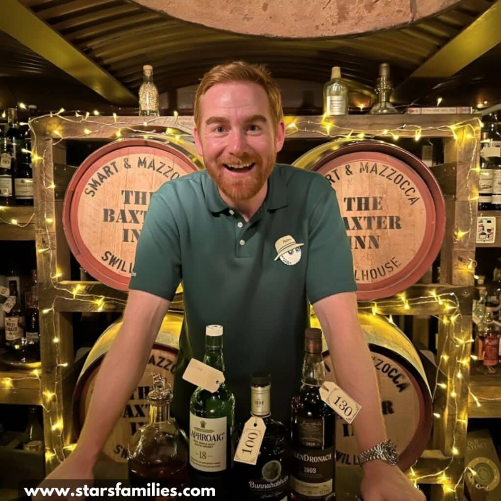 Andrew Santino, dressed in a green polo shirt with a "Nick" name tag, is behind a bar counter displaying bottles.