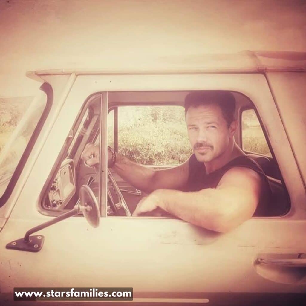 in a old image Ryan Paevey sitting in a car.