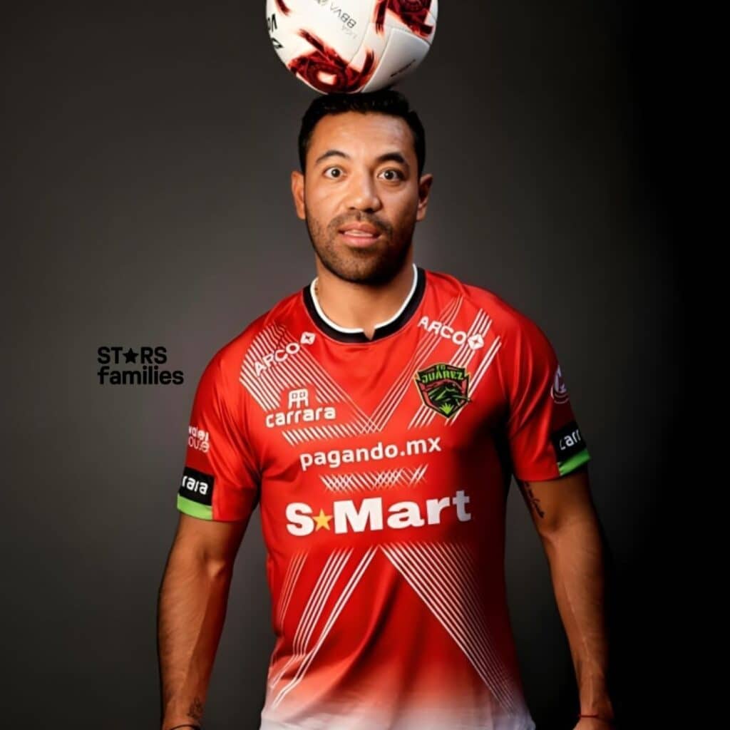 Marco Fabián, wearing a red soccer jersey with various sponsor logos, balances a soccer ball on his head. His face is blurred for privacy. The jersey has the following text and logos: "S-Mart" in large white letters with a star symbol, "pagando.mx" below the S-Mart logo, "carrara" on the upper left chest area, "ARCO" on the upper right chest area, "Juárez" with a logo on the left chest area, and "carrara" on the right sleeve.