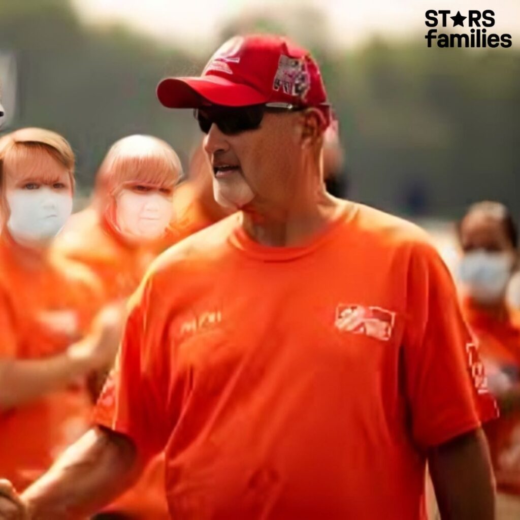 In an outdoor setting, Frank Siller, along with a group of people, wears matching orange shirts and red caps.