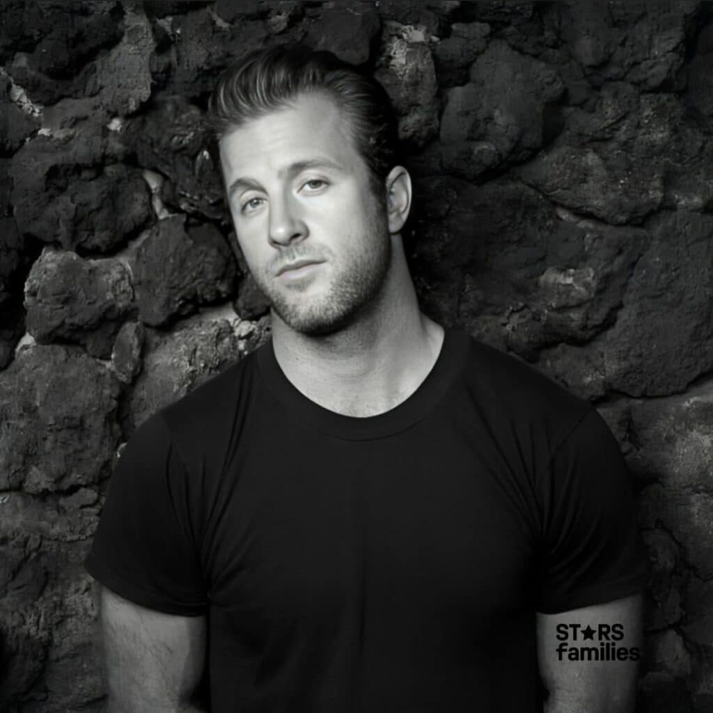 in black and white photo, Scott Caan standing in front of a wall.