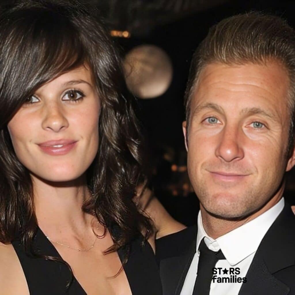 Scott Caan and Kacy Byxbee stand together at a red carpet event. Scott is dressed in a black suit with a white shirt and a black tie, while Kacy is wearing a stunning black dress.