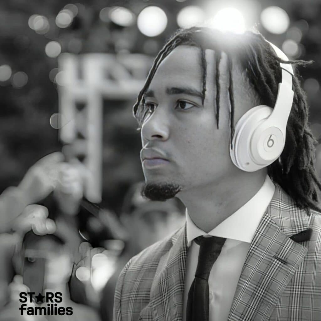 C.J. Stroud, wearing a suit and tie, is seen with a pair of white Beats headphones over his ears. His face is intentionally blurred for privacy.