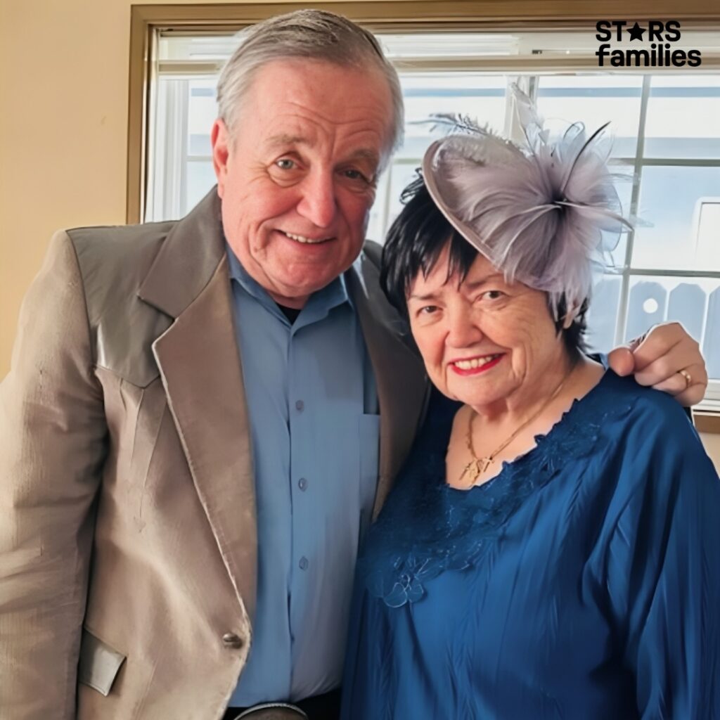 In a family photo, Jerry Mathers stands next to his mother, who is dressed in a light-colored dress.