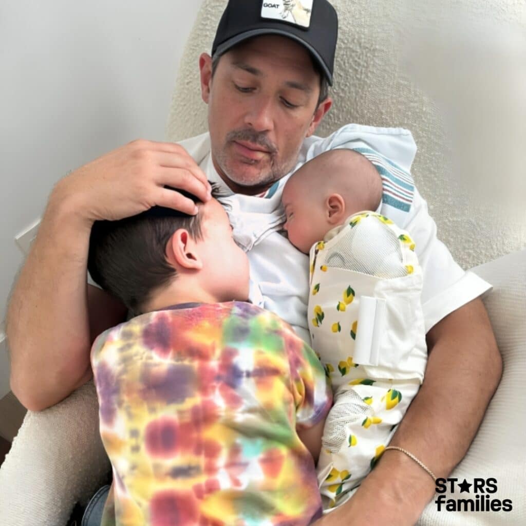  Steve Kazee joyfully holds two babies and a child, showcasing a heartwarming family moment filled with love.