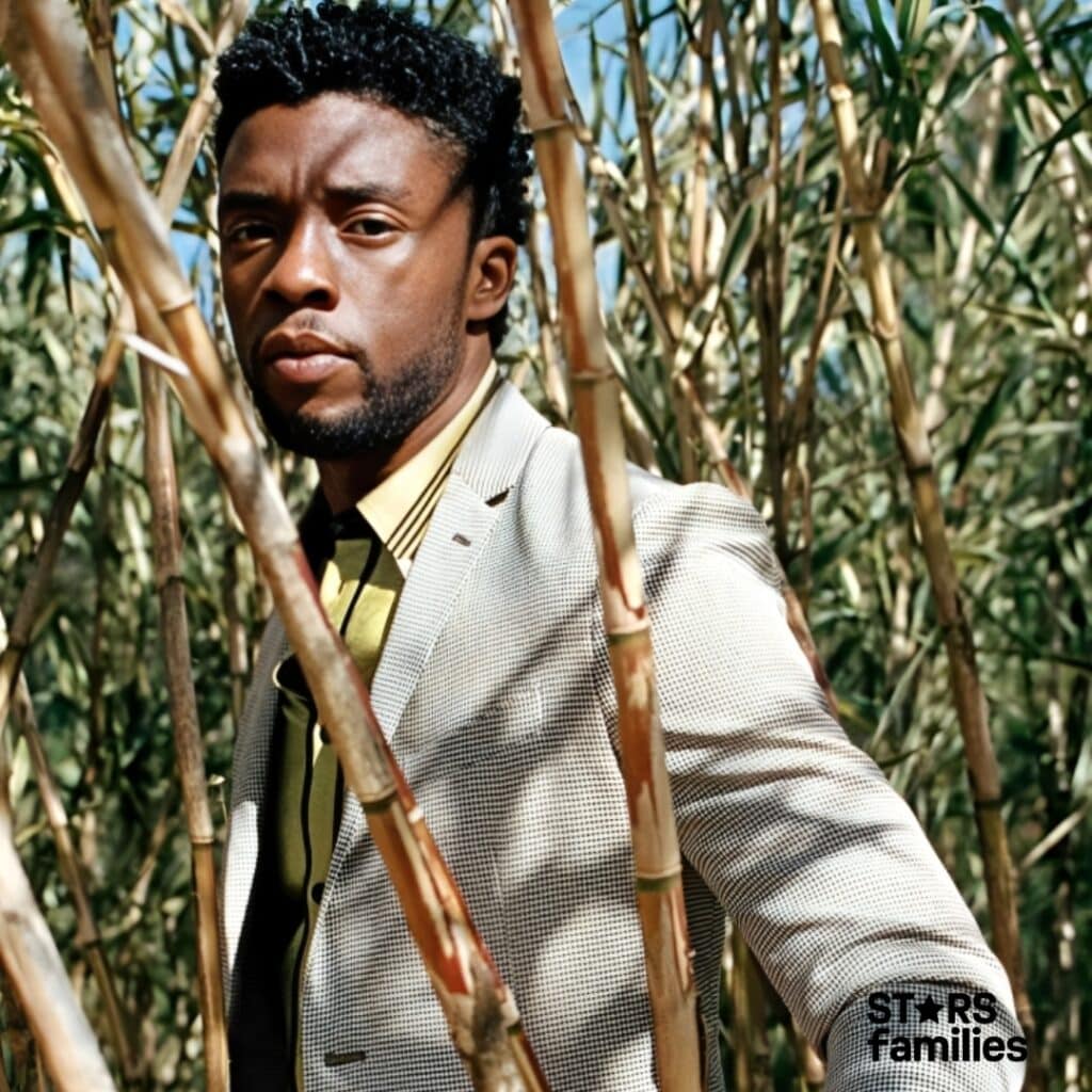 Chadwick Boseman stands among tall, thin bamboo stalks, wearing a light-colored, checkered blazer over a yellow shirt.