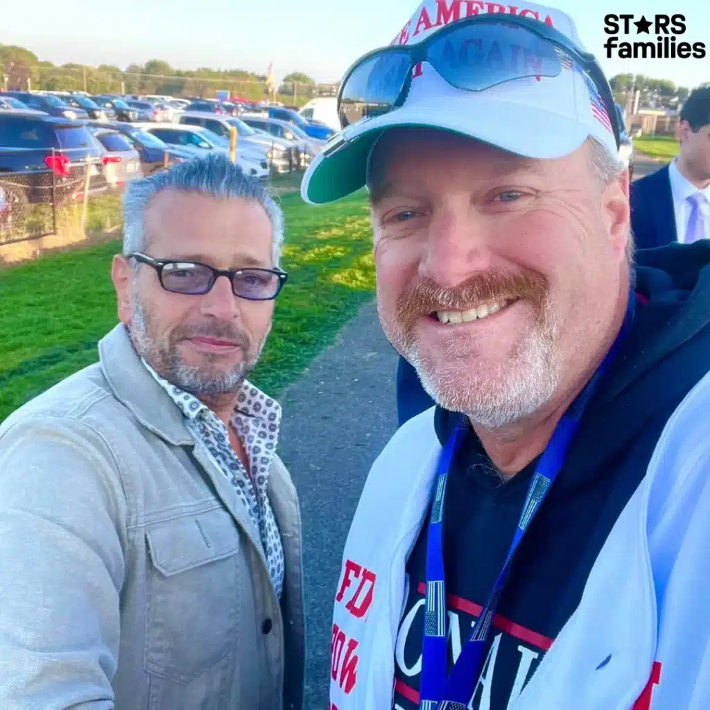 Scott Lobaido and another man pose happily for a photo at a lively baseball game.
