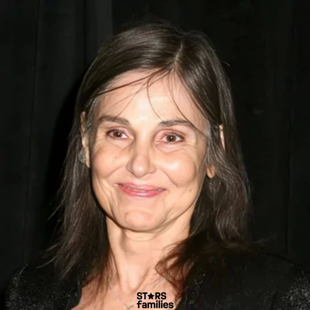 Paula Prentiss, dressed in a black outfit, stands against a dark background.